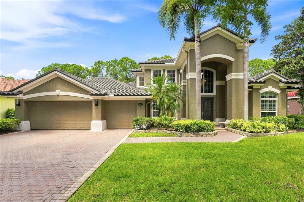 A two-story house with a tile roof, three-car garage, and a brick paver driveway — 7239 BRYCE POINT N, PINELLAS PARK, FL