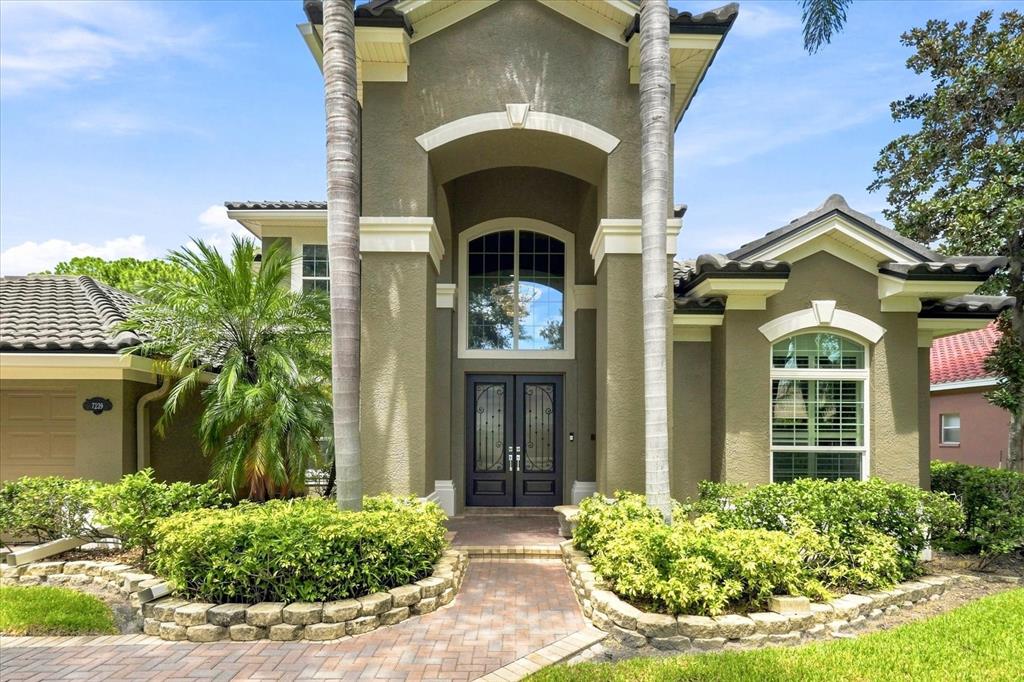 The front exterior of a two-story house features a brick walkway and two palm trees — 7239 BRYCE POINT N, PINELLAS PARK, FL