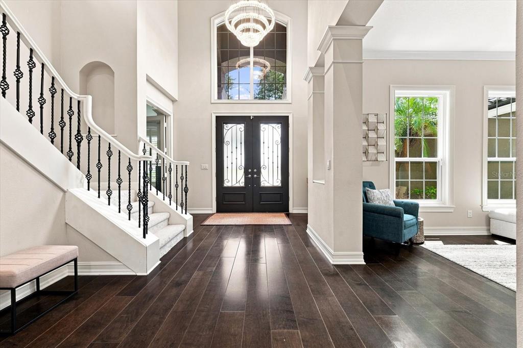 A bright foyer features dark hardwood floors, a grand staircase, and a double front door — 7239 BRYCE POINT N, PINELLAS PARK, FL
