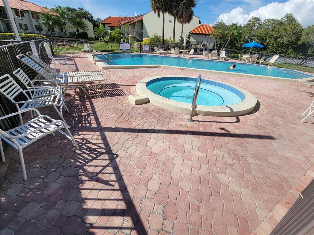 A swimming pool and circular hot tub are surrounded by a brick patio and lounge chairs — 1515 PINELLAS BAYWAY S UNIT 38, TIERRA VERDE, FL