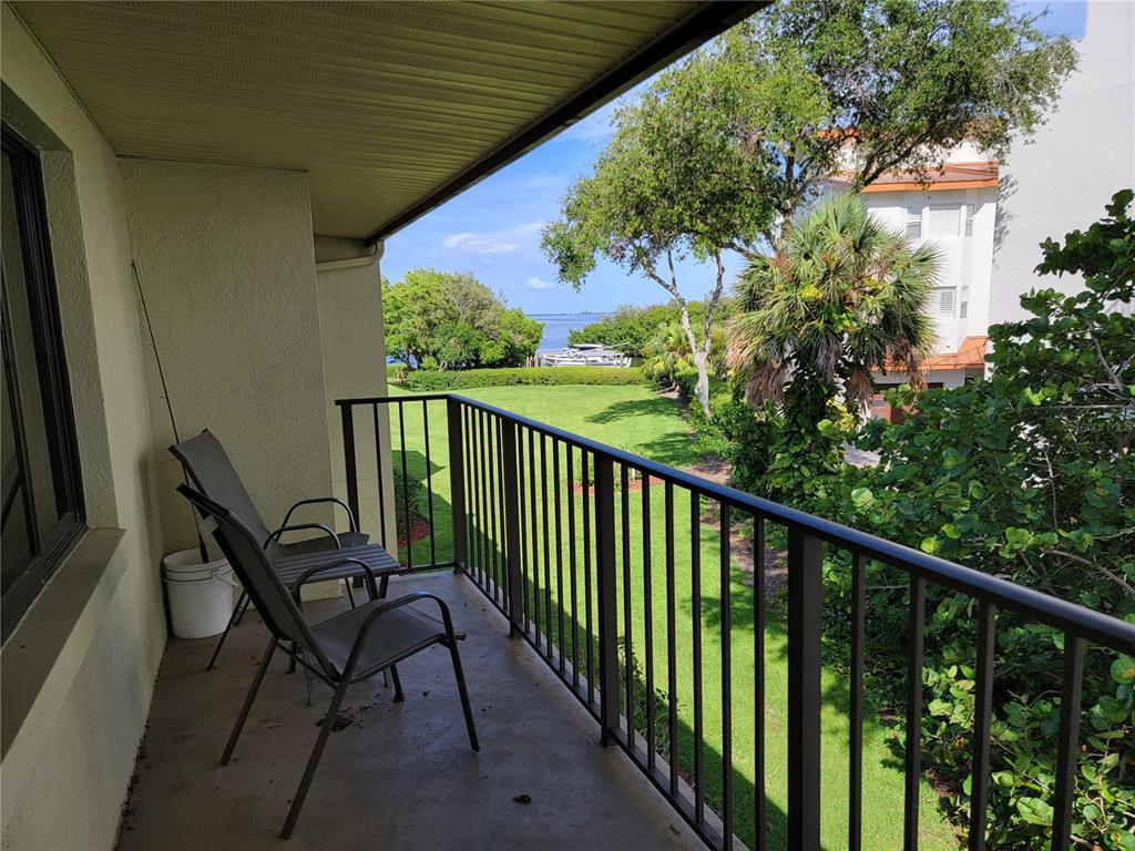 A covered balcony features two chairs, a metal railing, and a view of the water — 1515 PINELLAS BAYWAY S UNIT 38, TIERRA VERDE, FL