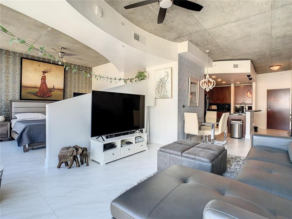 A studio apartment features a concrete ceiling, a partial room divider, and a modern kitchen — 155 S COURT AVENUE UNIT 1810, ORLANDO, FL