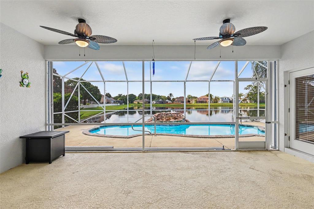 A covered patio features two ceiling fans, a screened enclosure, and a view of a pool — 423 STONEHENGE CIRCLE, ROCKLEDGE, FL