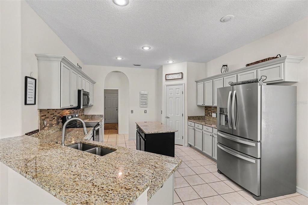 A kitchen features granite countertops, light gray cabinets, stainless steel appliances, and tile flooring — 423 STONEHENGE CIRCLE, ROCKLEDGE, FL