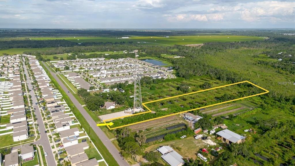 An aerial view shows a rectangular plot of land outlined in yellow near a neighborhood — 11105 SUMNER ROAD, WIMAUMA, FL