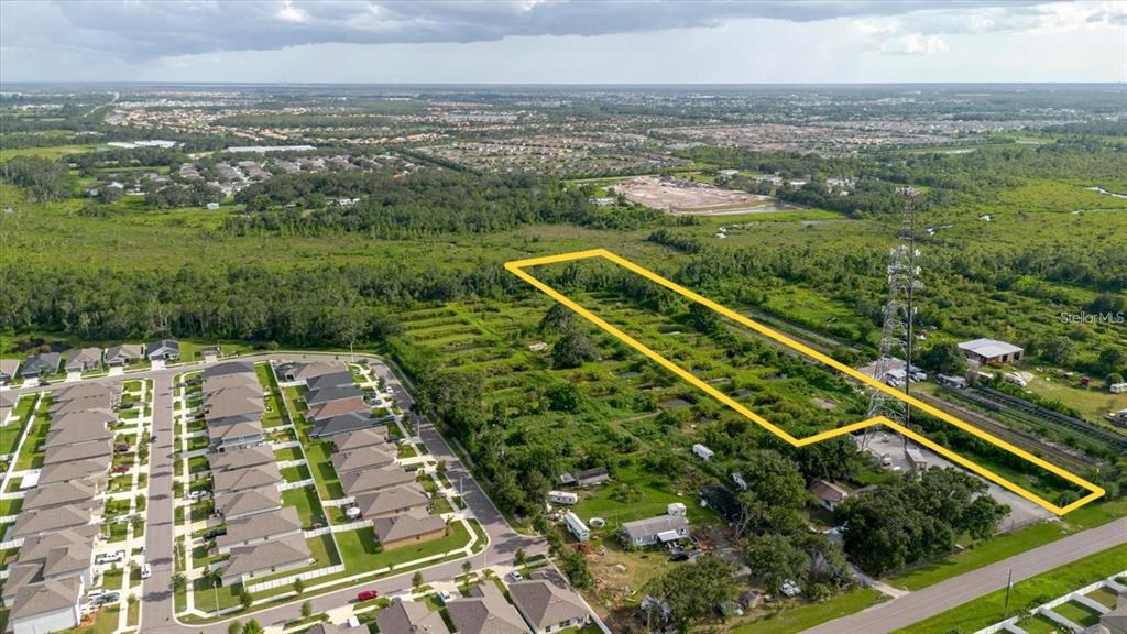 An aerial view shows a rectangular plot of land outlined in yellow near a neighborhood — 11105 SUMNER ROAD, WIMAUMA, FL