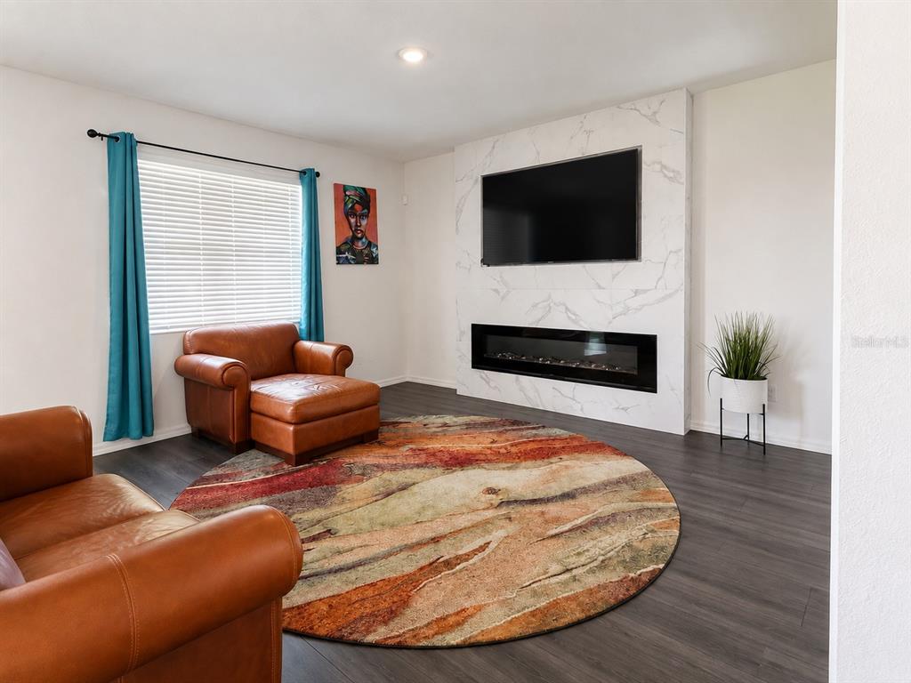 A living room features a marble fireplace wall, a circular rug, and brown leather furniture — 9589 SANDY BLUFFS CIRCLE, PARRISH, FL