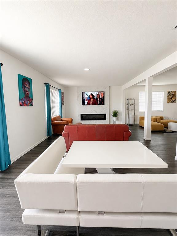 An open-concept living and dining area features a white banquette, red sofa, and fireplace — 9589 SANDY BLUFFS CIRCLE, PARRISH, FL