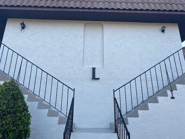 An exterior view of a white building with a central letter L and two staircases — 92 WINDTREE LANE UNIT 201, WINTER GARDEN, FL