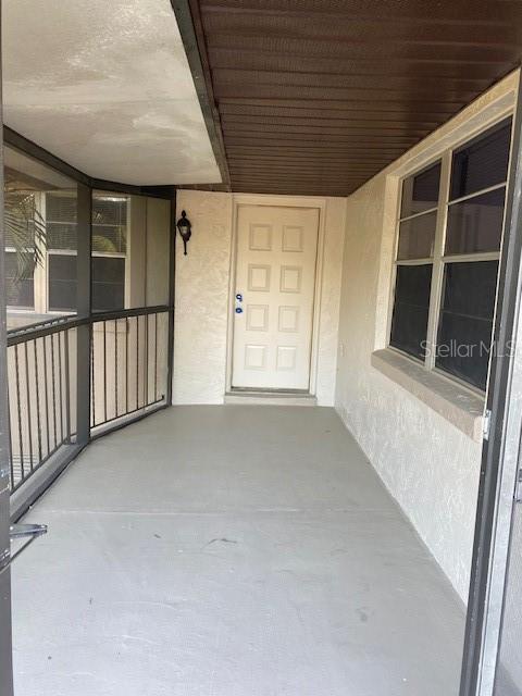 A covered porch features a white front door, gray flooring, and a screened-in railing — 92 WINDTREE LANE UNIT 201, WINTER GARDEN, FL