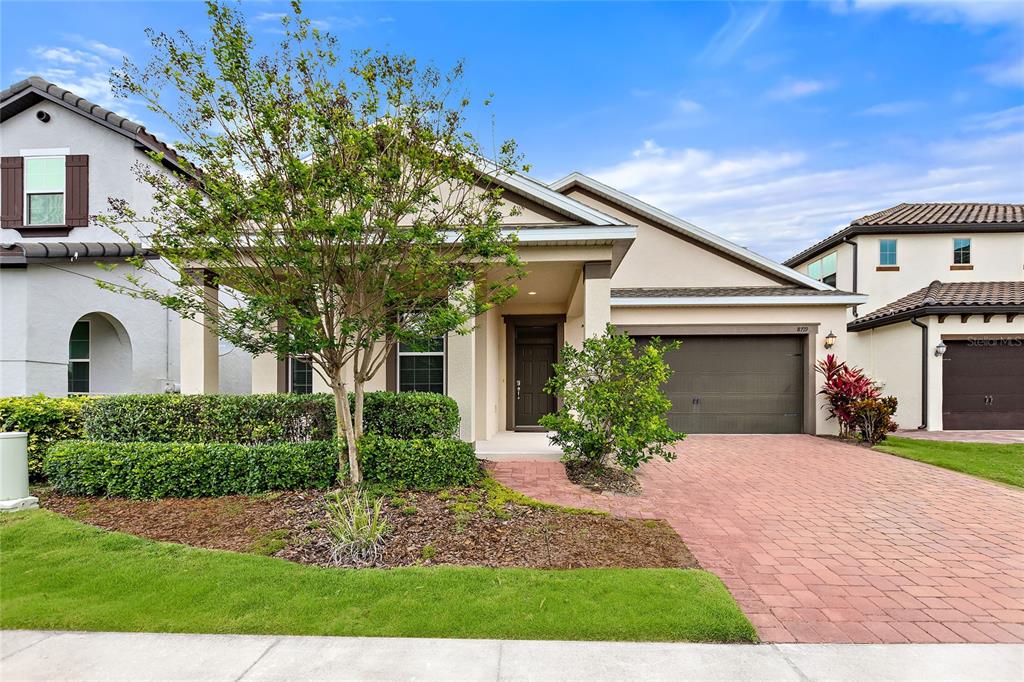 A single-story house with a brick driveway, a two-car garage, and a landscaped front yard — 8719 CRESCENDO AVENUE, WINDERMERE, FL