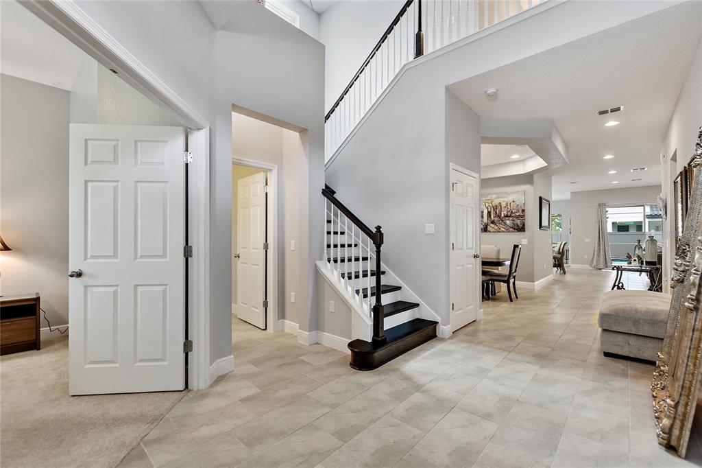 A foyer with tile flooring features a staircase with dark wood treads and white railings — 8719 CRESCENDO AVENUE, WINDERMERE, FL