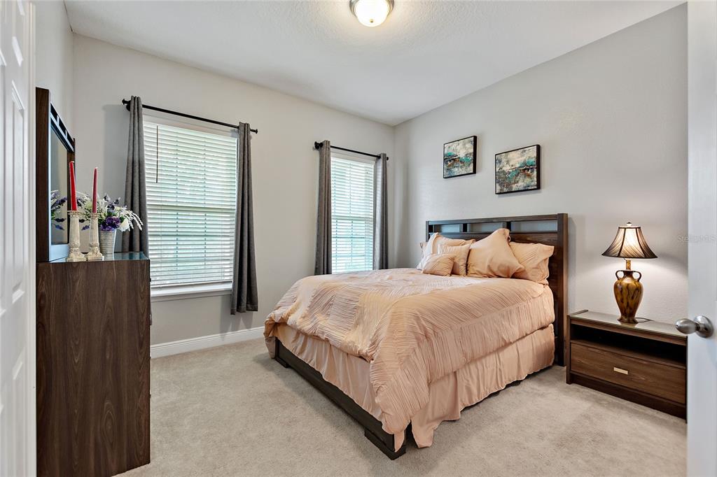 A bedroom features a queen bed, two windows with dark curtains, and a wooden dresser — 8719 CRESCENDO AVENUE, WINDERMERE, FL