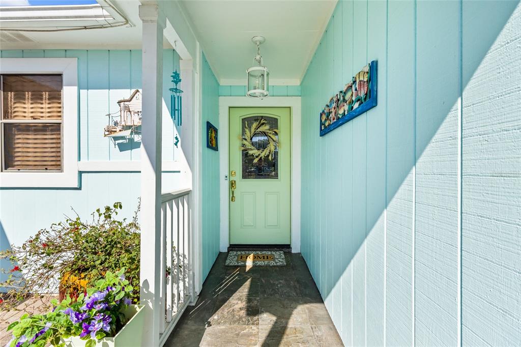 A light blue house exterior features a white garage door, a small porch, and landscaping — 6609 MAUNA LOA BOULEVARD, SARASOTA, FL