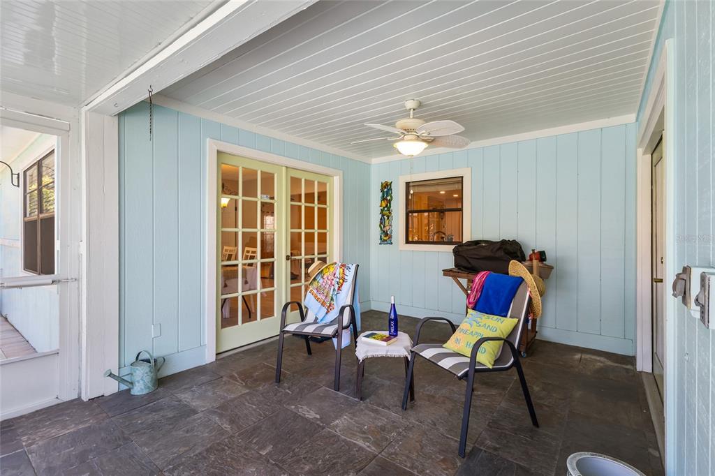 A covered patio with tile flooring overlooks a backyard swimming pool and fenced lawn — 6609 MAUNA LOA BOULEVARD, SARASOTA, FL