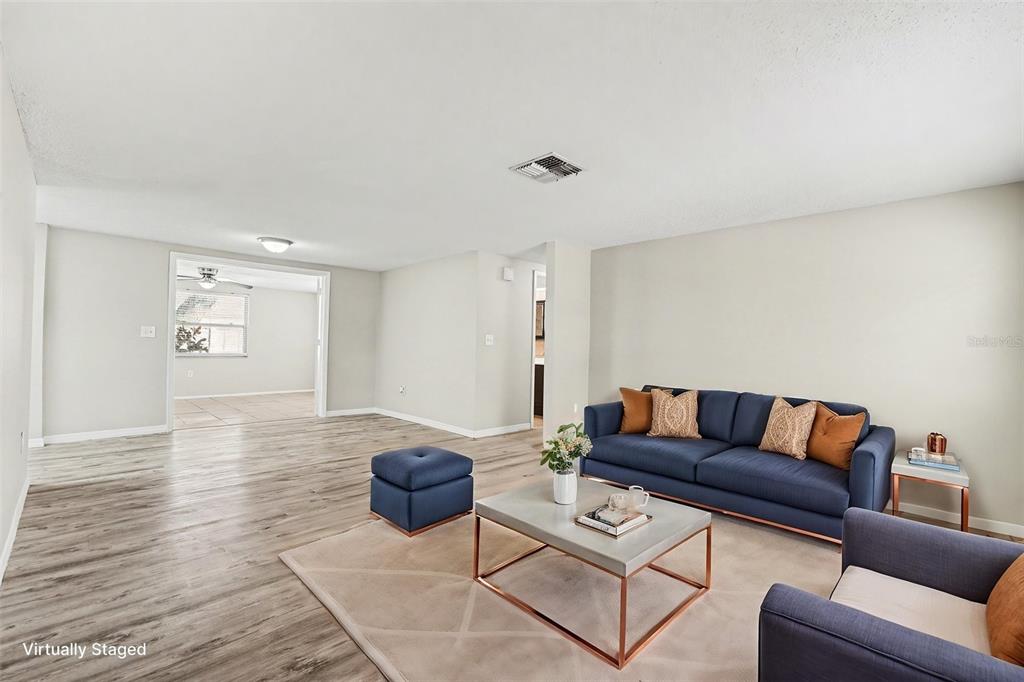 An empty living room with light gray walls, wood-look flooring, and a white front door — 7255 FIRESIDE DRIVE, PORT RICHEY, FL
