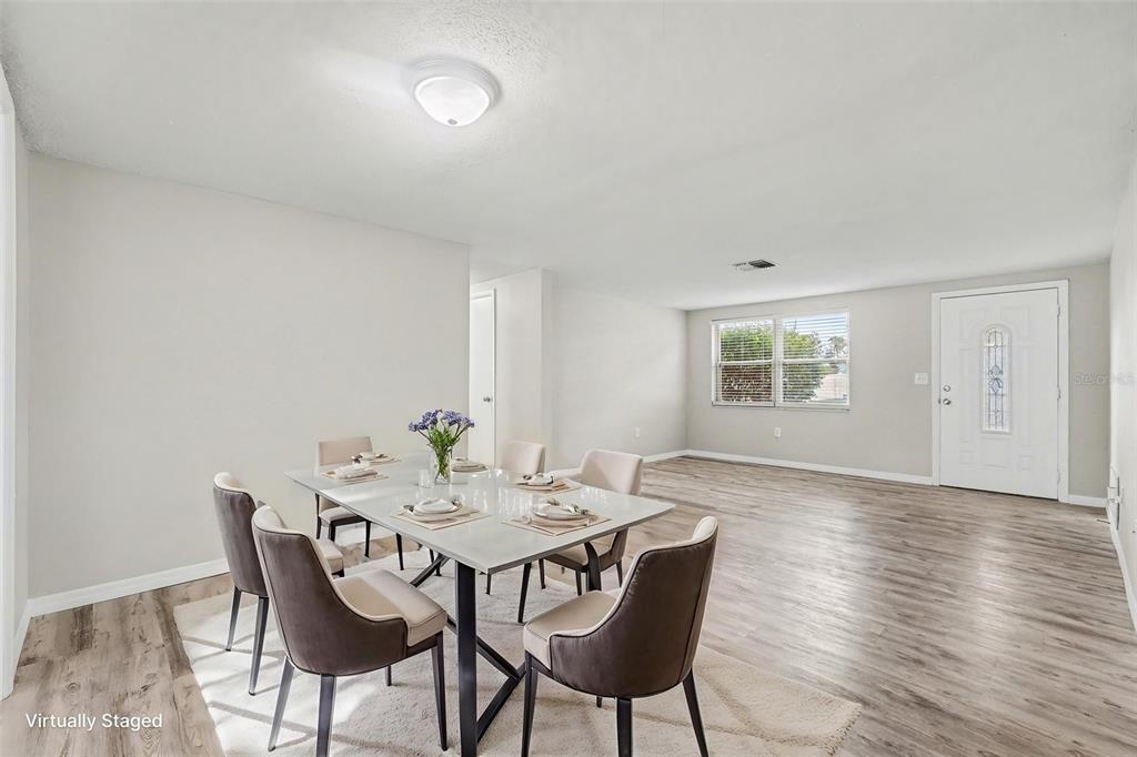 An empty room with light gray walls and wood-look flooring leads to an adjacent space — 7255 FIRESIDE DRIVE, PORT RICHEY, FL