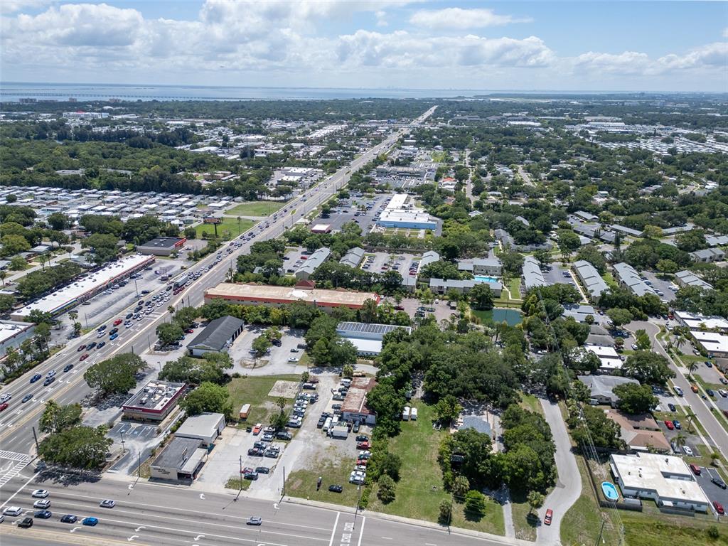 This aerial view shows a commercial area with a multi-lane road and surrounding residential properties — 191 BELCHER ROAD S, LARGO, FL