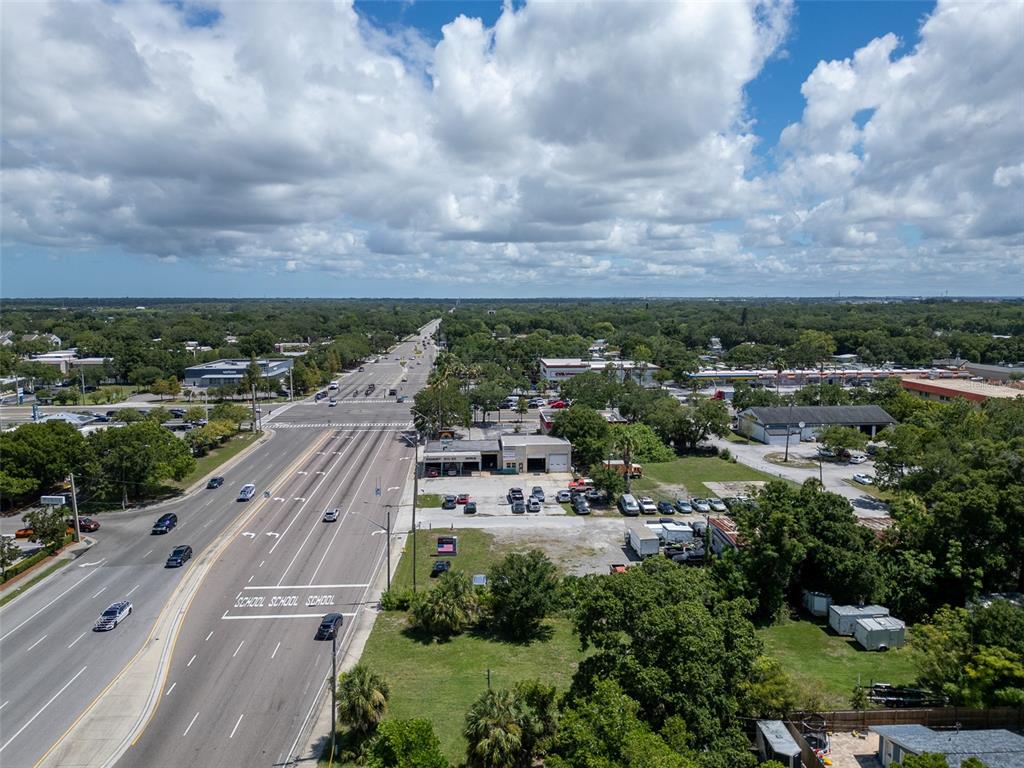 An aerial view shows a multi-lane road with school markings alongside commercial buildings and trees — 191 BELCHER ROAD S, LARGO, FL