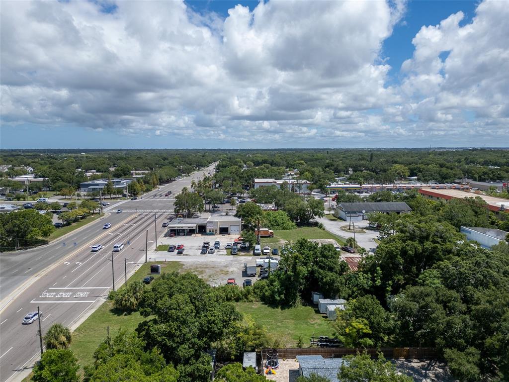 An aerial view shows a commercial property with a parking lot next to a road — 191 BELCHER ROAD S, LARGO, FL