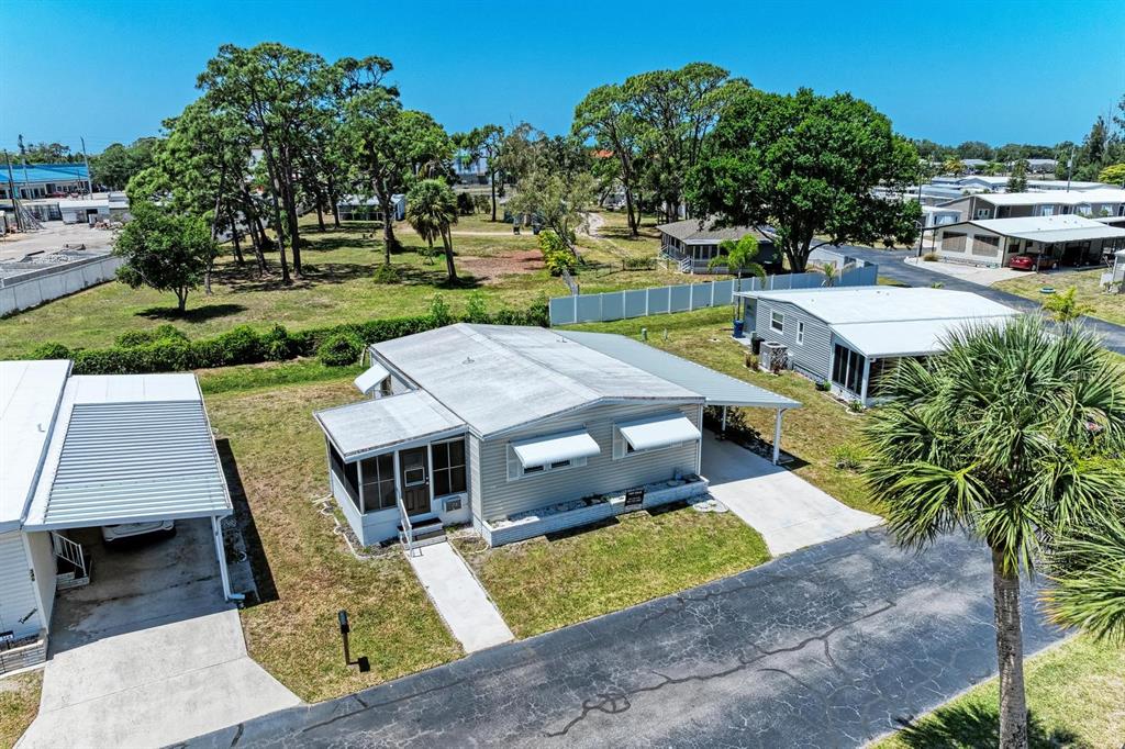 An aerial view shows a light-colored mobile home with a carport and a screened porch — 348 TROPIC DRIVE, OSPREY, FL