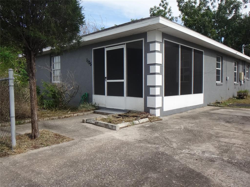 A gray covered porch features a white front door, a window, and a screened enclosure — 1125 BRITTS LANE, BARTOW, FL