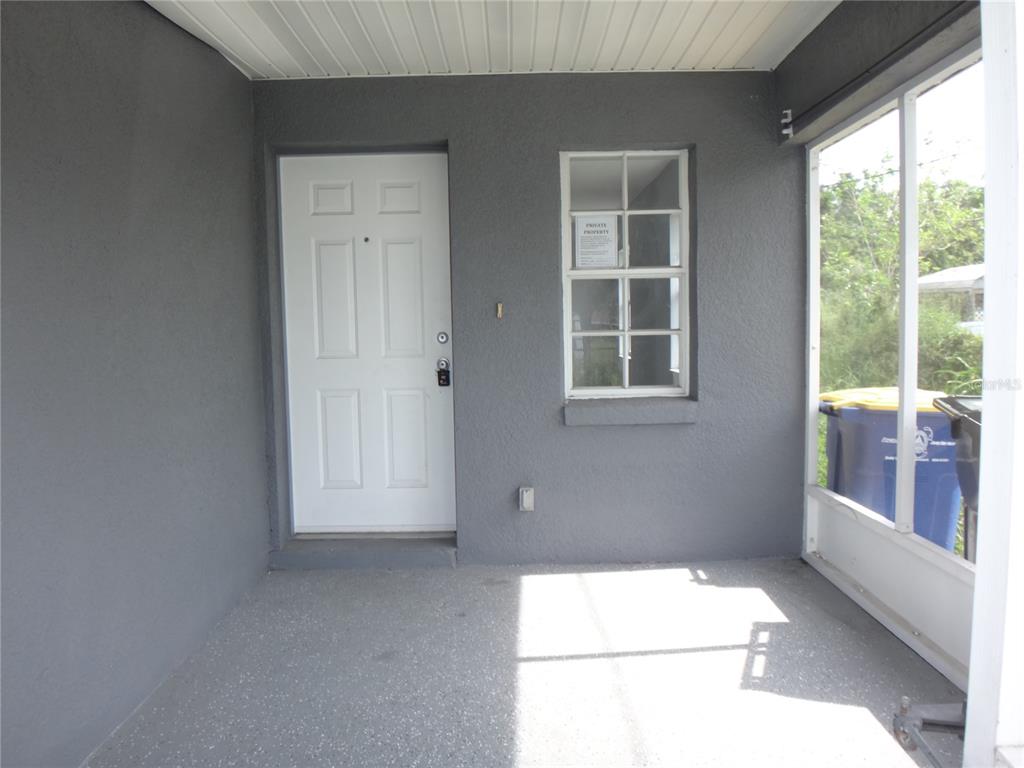 A gray covered porch features a white front door, a window, and a screened enclosure — 1125 BRITTS LANE, BARTOW, FL