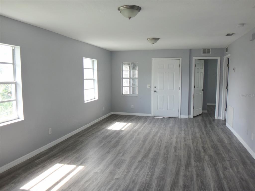A kitchen with white cabinets, stainless steel appliances, gray tile backsplash, and wood-look flooring — 1125 BRITTS LANE, BARTOW, FL