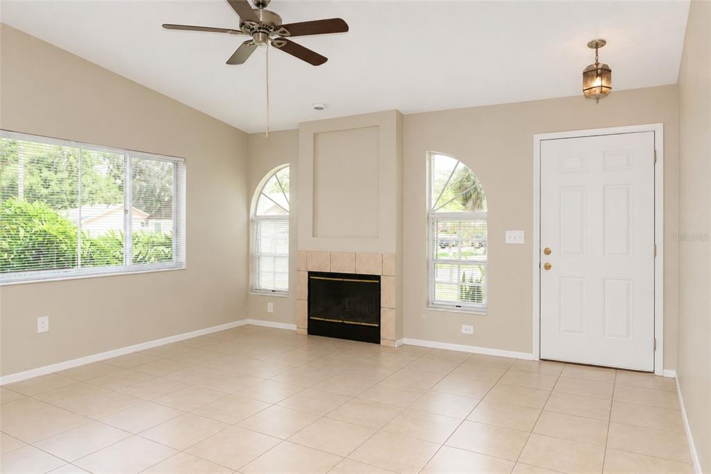 A living room with tile flooring, a fireplace, a ceiling fan, and a white front door — 4631 W EASTWIND DRIVE, PLANT CITY, FL