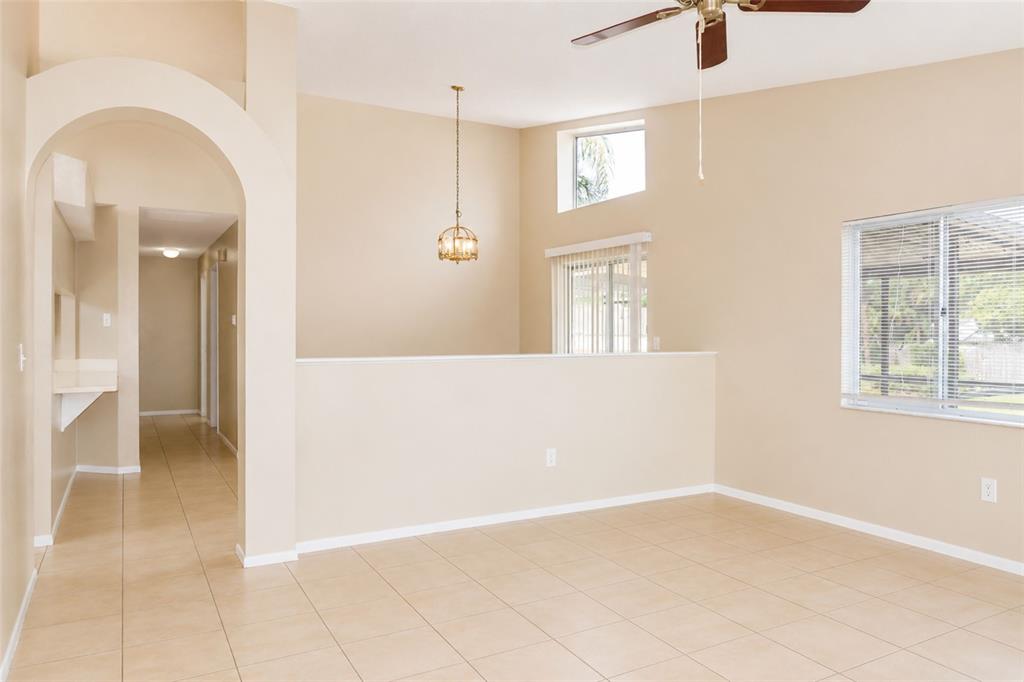 An empty room with beige walls, tile flooring, an arched entryway, and a ceiling fan — 4631 W EASTWIND DRIVE, PLANT CITY, FL
