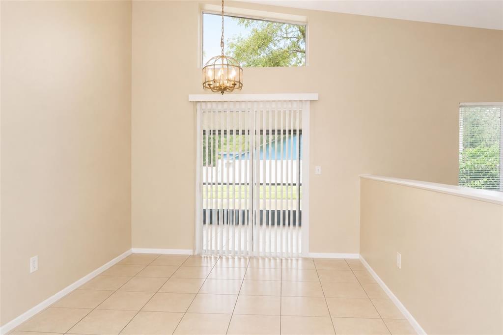 A dining area features tile flooring, a vaulted ceiling, a chandelier, and sliding glass doors — 4631 W EASTWIND DRIVE, PLANT CITY, FL