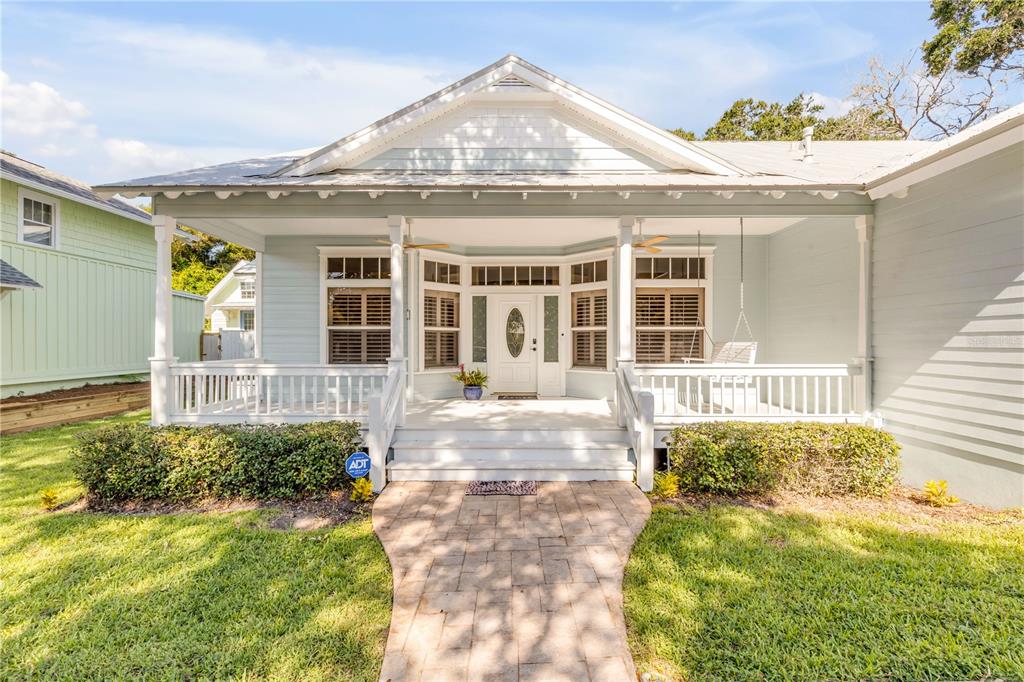 A light blue cottage with a covered front porch, white railings, and a stone walkway — 410 S PENINSULA AVENUE, NEW SMYRNA BEACH, FL