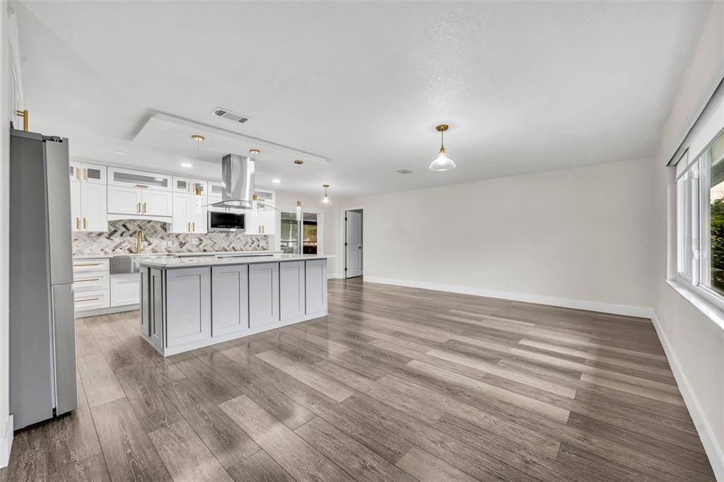 A modern kitchen features white cabinetry, a large island, and wood-look flooring in an open space — 40 BLARE DRIVE, PALM COAST, FL
