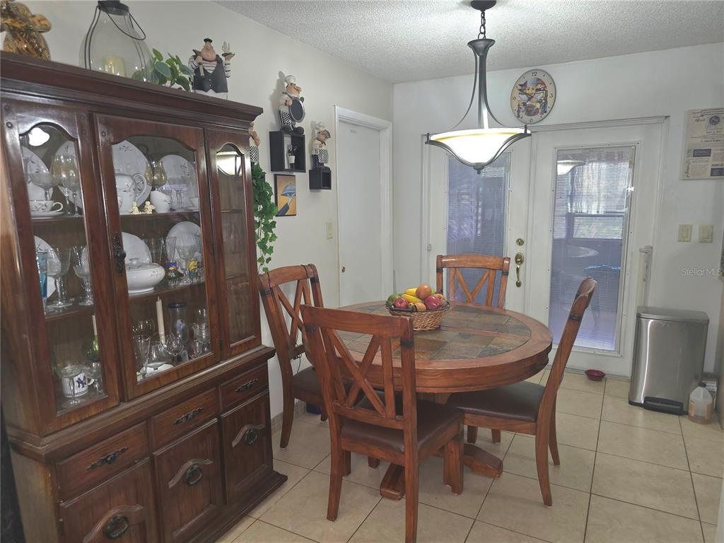 A dining area features a wooden hutch, a round table with chairs, and tile flooring — 7051 VALLEJO WAY, NEW PORT RICHEY, FL