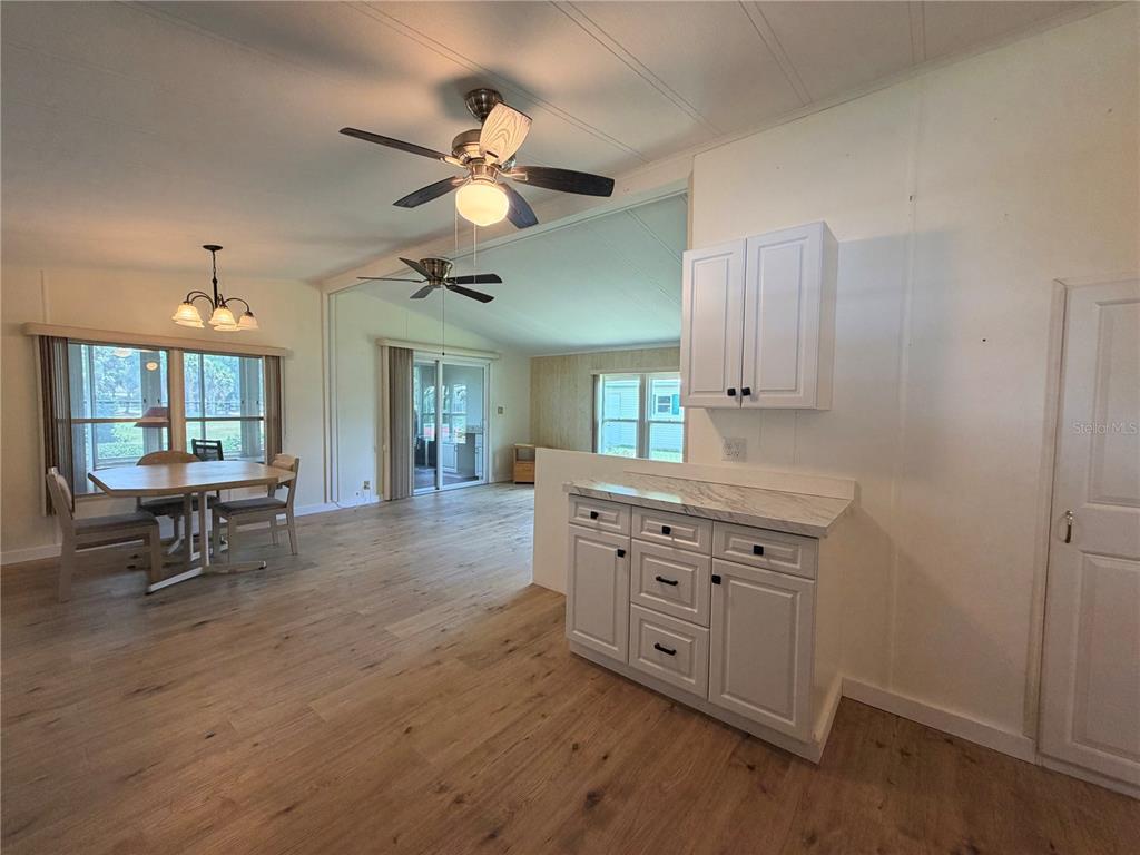 A kitchen area with white cabinets and a marble countertop overlooks a dining room — 7445 MORIAH AVENUE, BROOKSVILLE, FL
