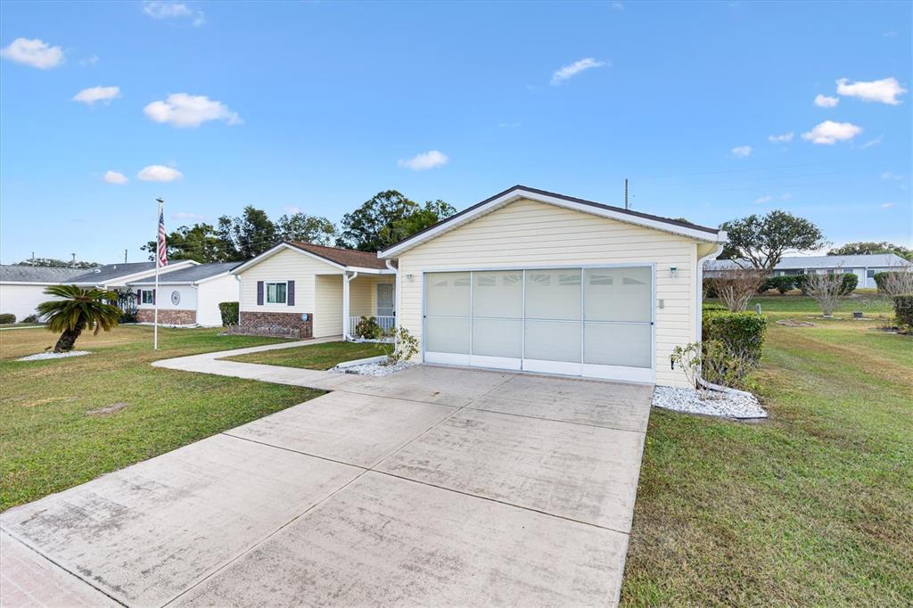 A single-story house with light yellow siding, a concrete driveway, and a large garage door — 10767 SE 174TH LOOP, SUMMERFIELD, FL