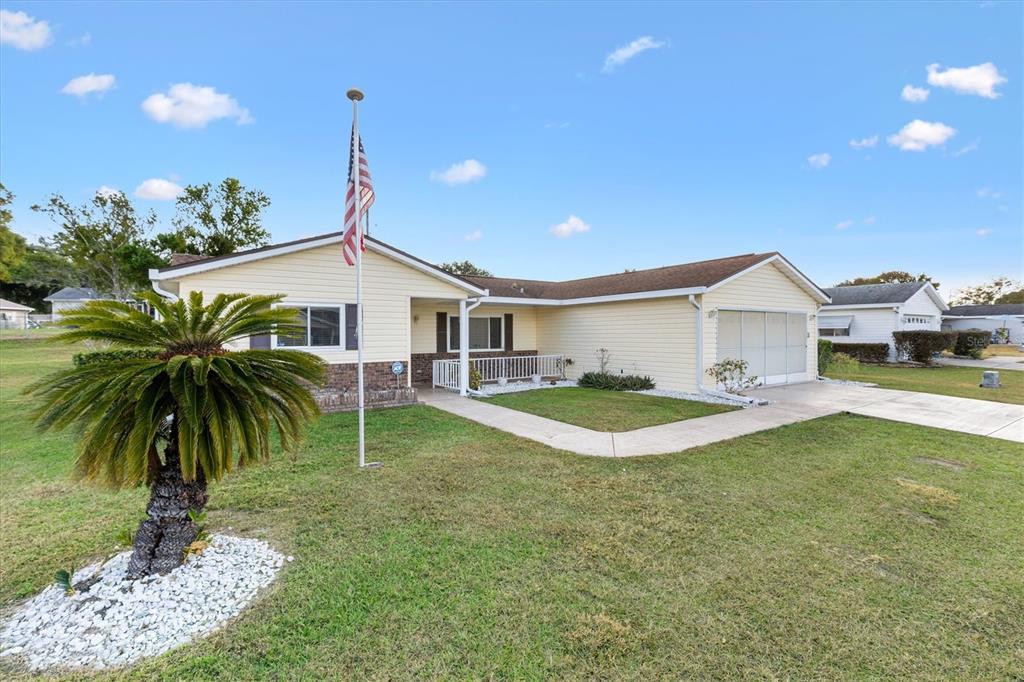 A single-story house with light yellow siding, a flag pole, and a palm tree — 10767 SE 174TH LOOP, SUMMERFIELD, FL