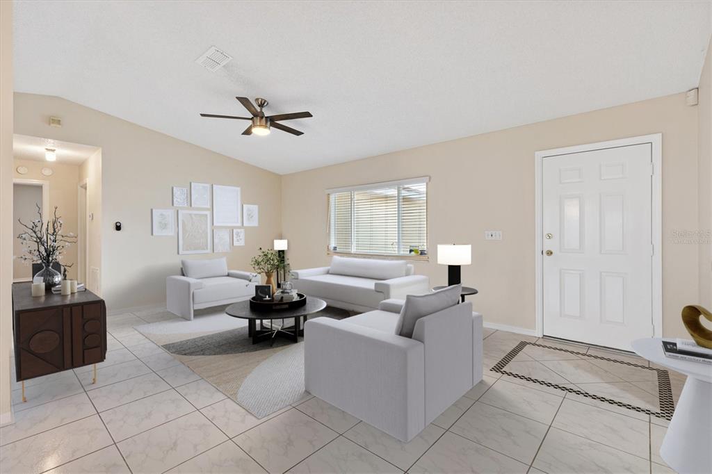 A living room features white tile flooring, a ceiling fan, and a neutral furniture arrangement — 10767 SE 174TH LOOP, SUMMERFIELD, FL
