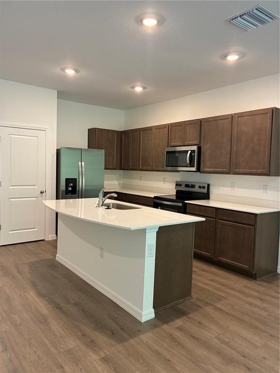 A kitchen features dark wood cabinets, white countertops, a center island, and stainless steel appliances — 32519 MIDSUMMER NIGHT LANE, WESLEY CHAPEL, FL