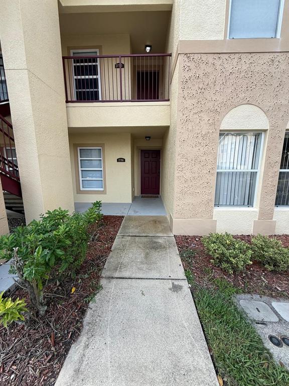 A two-story tan stucco building features a covered entryway, a balcony, and arched windows — 2776 CLUB CORTILE CIRCLE UNIT A, KISSIMMEE, FL