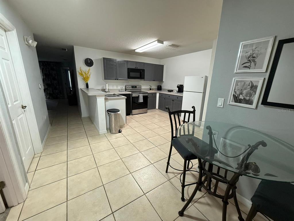 A bedroom features a bed with a dark headboard, carpeted flooring, and a ceiling fan — 2776 CLUB CORTILE CIRCLE UNIT A, KISSIMMEE, FL