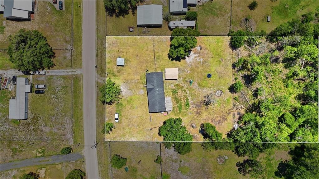 An aerial view shows a single-story house on a large, fenced, grassy lot with trees — 10724 PATHFINDER TRAIL, LAKELAND, FL
