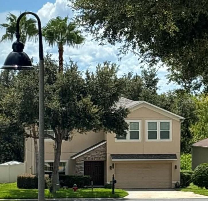 A two-story house with tan siding, a stone-accented entryway, and a two-car garage — 2979 ETOWAH PARK BOULEVARD, TAVARES, FL