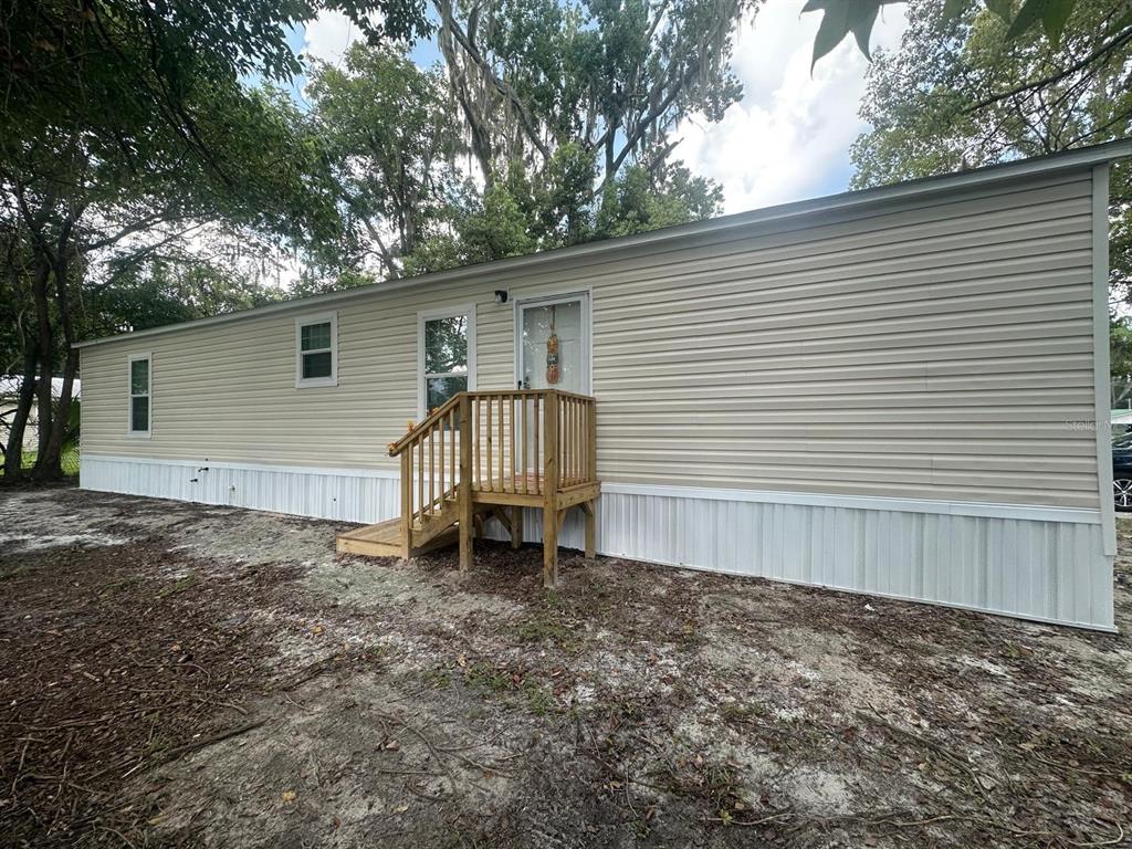 A light-colored mobile home exterior features a wooden staircase leading to a front entry door — 862 NE COLDWATER AVENUE, LAKE CITY, FL