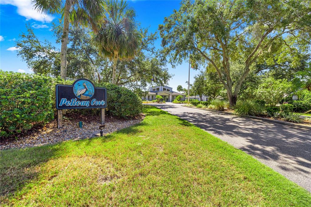 A sign for Pelican Cove stands beside a paved driveway leading to a building — 11043 W HARBOR WATCH LOOP, CRYSTAL RIVER, FL