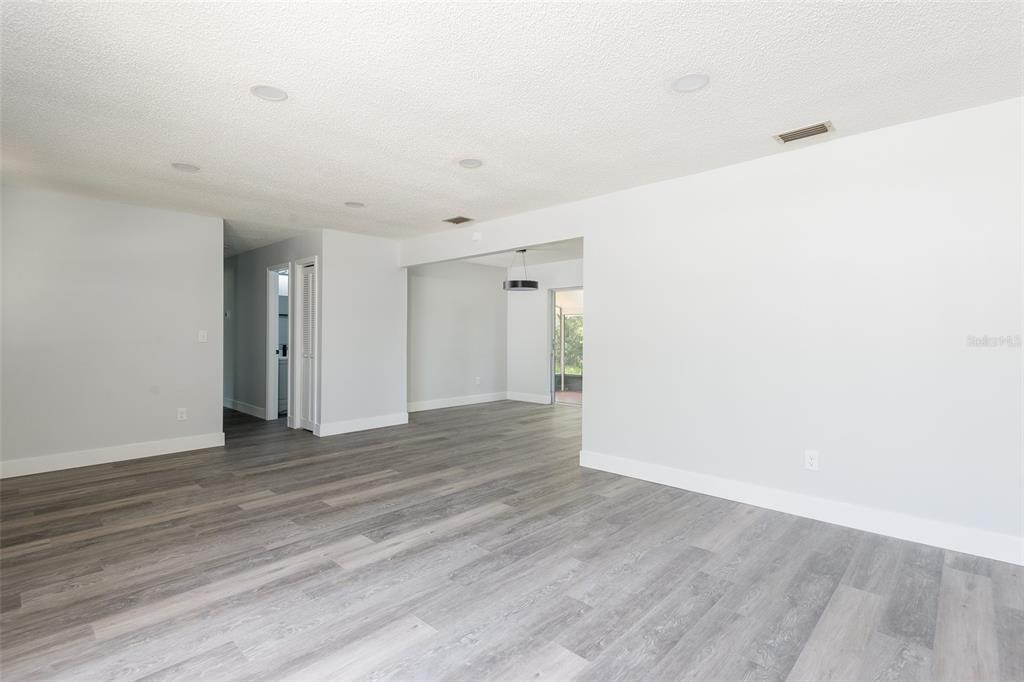 An open-concept living area features light gray walls, wood-look flooring, and recessed ceiling lighting — 902 SHANGRI LA DRIVE, SEFFNER, FL