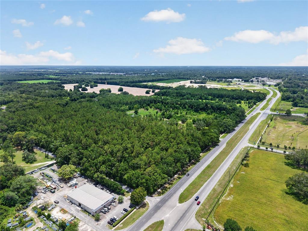 An aerial view shows a large wooded lot next to a highway and industrial building — 000 W NEWBERRY ROAD, NEWBERRY, FL