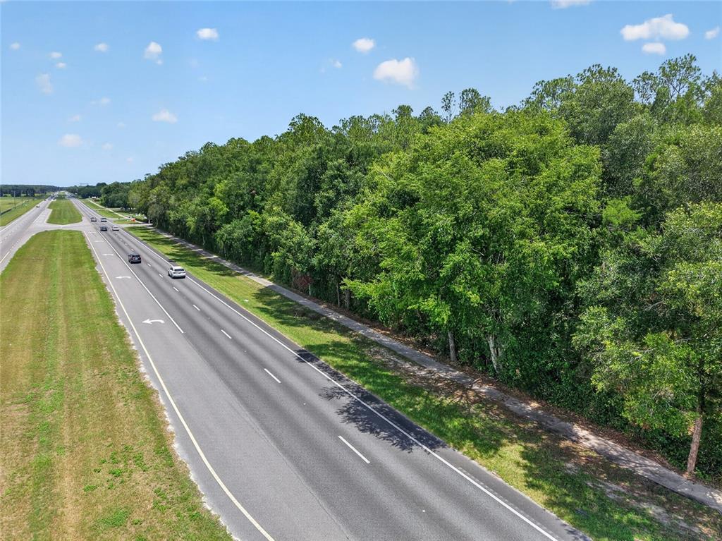 An aerial view shows a multi-lane road running alongside a dense, wooded lot — 000 W NEWBERRY ROAD, NEWBERRY, FL