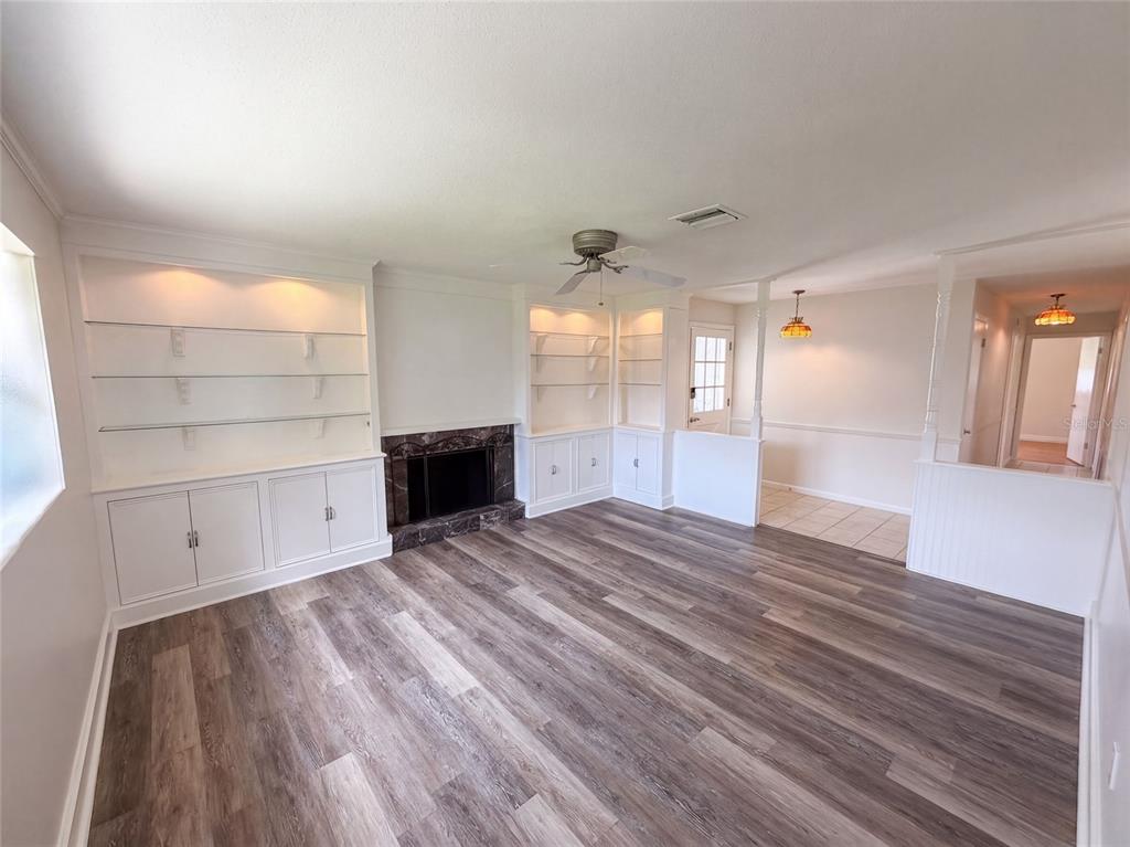 A living room with wood-look flooring, built-in shelving, and a marble-surround fireplace — 2617 S FAIRWAY DRIVE, MELBOURNE, FL