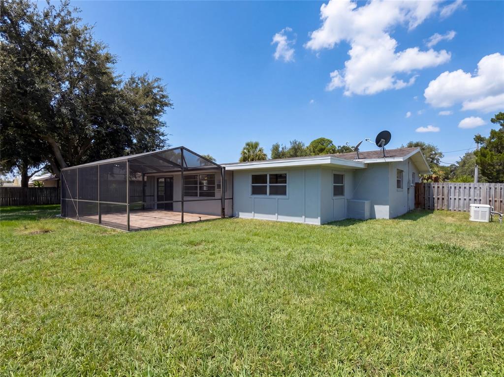 The backyard features a light-colored house with a screened-in patio and a satellite dish — 2617 S FAIRWAY DRIVE, MELBOURNE, FL